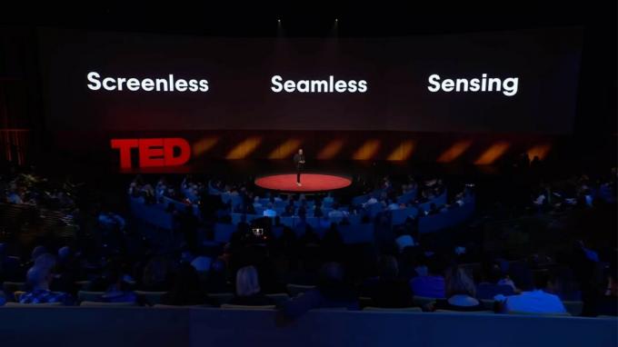 Имран Чаудри стоит на сцене во время выступления TED с фразой «Безэкранное бесшовное зондирование», написанной на слайде позади него.