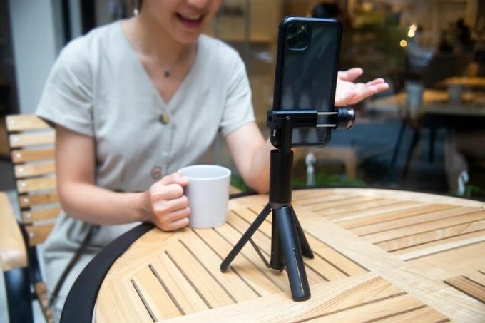 ადამიანი FaceTime ზარზე iPhone-ით, რომელიც დამონტაჟებულია EasySelfie-ში, დგას მაგიდაზე