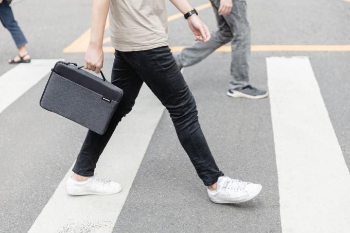 Um pedestre carrega uma bolsa SwitchEasy Urban para MacBook enquanto caminha na faixa de pedestres.